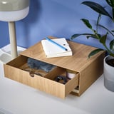 Desk organizer with drawer, compartments, and open top. On desk with plant and lamp.