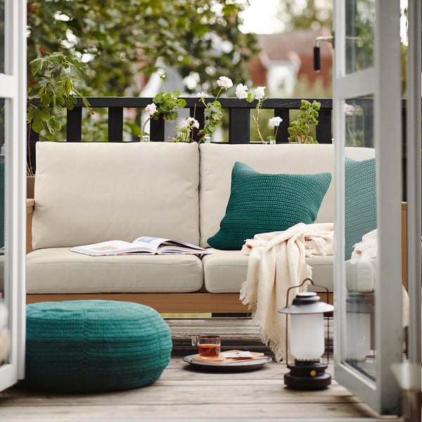 Balcony with HATTHOLMEN sofa, green & teal accessories, eucalyptus wood.