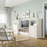 Modern living room with green walls, white HAUGA furniture, plants, and photos.