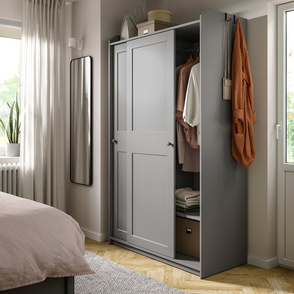 Modern bedroom with gray HAUGA wardrobe featuring hangers and shelves.