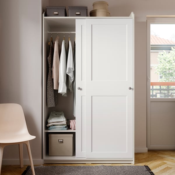 White HAUGA wardrobe with hanging & shelves, sliding doors, in organized room.