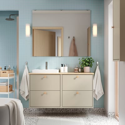 Modern bathroom with bamboo countertop vanity, mirror, and drawers. Includes wash-basin, towels, blue tiled walls, and speckled floor.