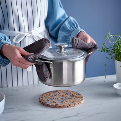 A HEAT round cork trivet with blue dots.