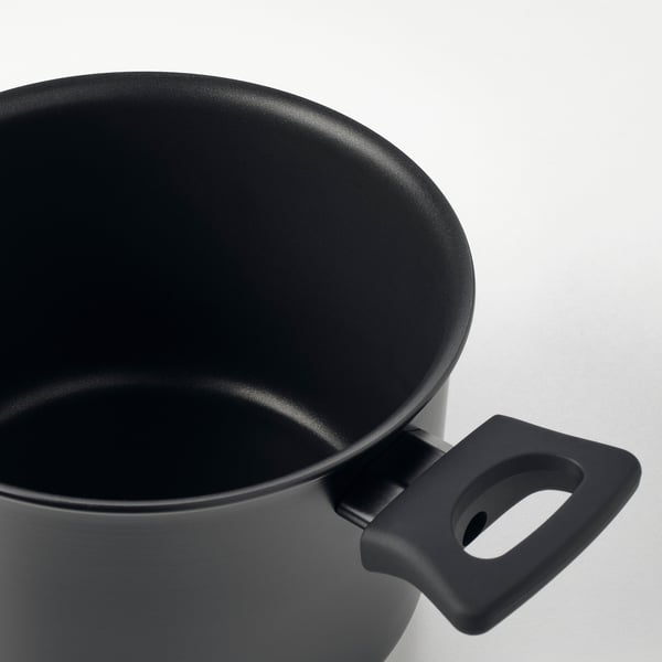 Close-up of black pots rim and sturdy handle, showcasing smooth interior and durable design.