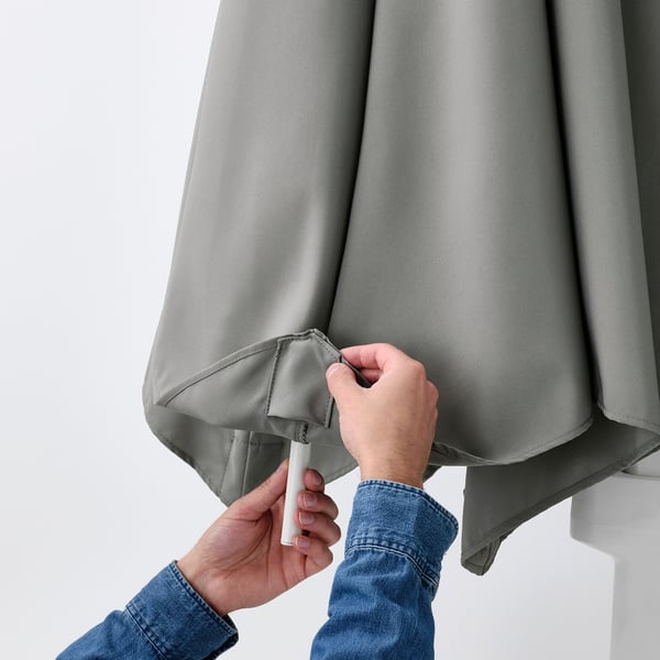 Person secures gray fabric, likely HÖGÖN parasol, to vent, helping heat circulate.