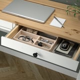 Organized desk drawer showing laptop, notebook, pen, mouse, and cables neatly arranged in compartments.