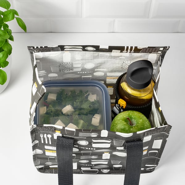 Bag with bottle holder, food container, and apple, pattern visible, on white surface.