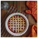 Freshly baked lattice pie cooling in ribbed dish.