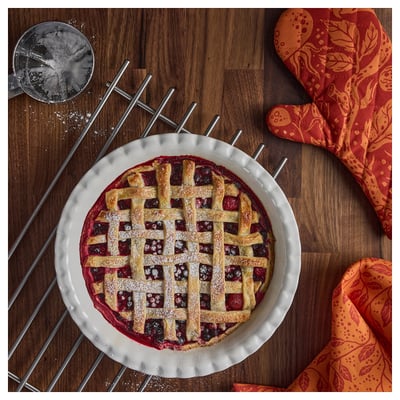 Freshly baked lattice pie cooling in ribbed dish.
