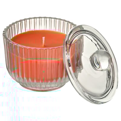 Clear glass fluted candle jar with lid holding bright orange scented candle.