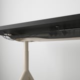 Desk with adjustable metal legs securing cables underneath.
