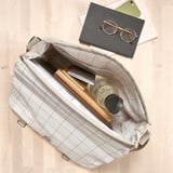 Open bag reveals water bottle, laptop, and notebook, showcasing its capacity for daily essentials.