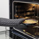 Person holding a baking dish with crumble topping, ready to be placed in the oven.