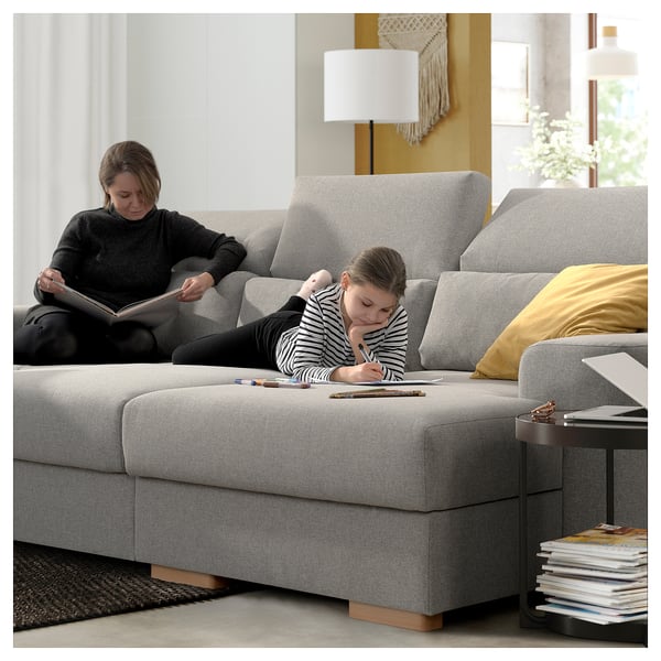 Two women relax on ISTABY sofa; one reads, the other draws. High backs, adjustable headrests.
