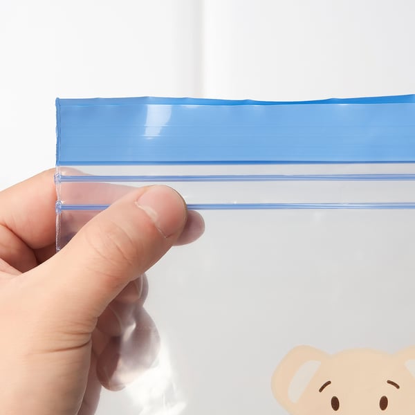 A hand holding an ISTAD bag by its blue seal, demonstrating its re-sealable feature.