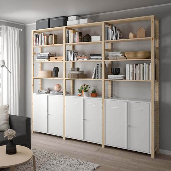 Modern living area with IVAR light wood bookcases and white cabinets; books, decor, plants, grey wall.