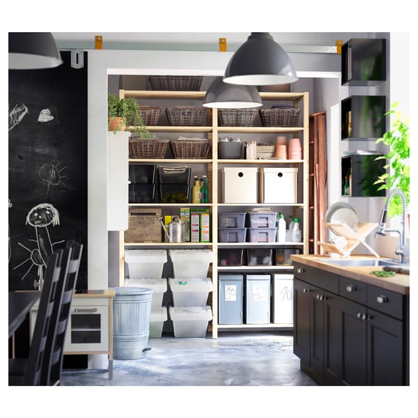 Modern kitchen with white IVAR shelves holding storage bins, baskets, and appliances, featuring hanging lights and a chalkboard wall.