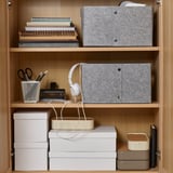Organized shelves with felt boxes, stationery, and headphones for storage and accessibility.