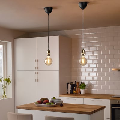 Modern kitchen with 2 JÄLLBY pendant lamps over wooden island, adorned with fruits and flowers.