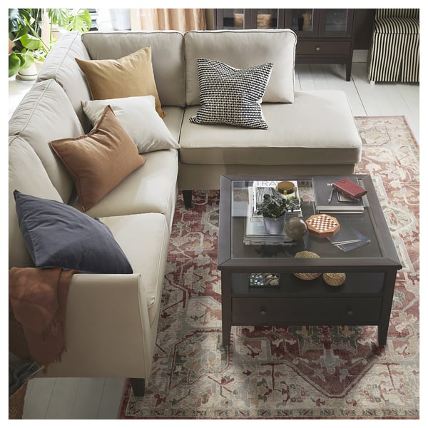 Modern living room with neutral sofa and colourful cushions on a patterned rug.
