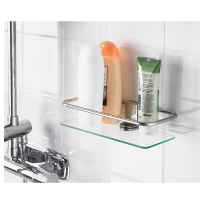 Clear glass shelf with chrome brackets holds toiletries. Mounts on bathroom wall for organized storage.
