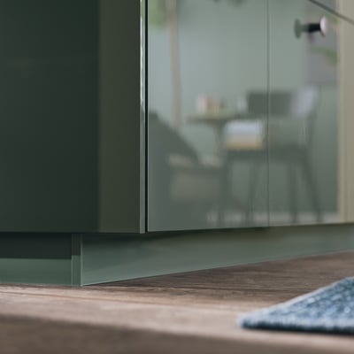 Modern kitchen with glossy green cabinet & wooden countertop.