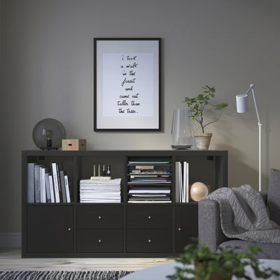 Modern living room with KALLAX shelf, books, plant, art, and cozy chair.