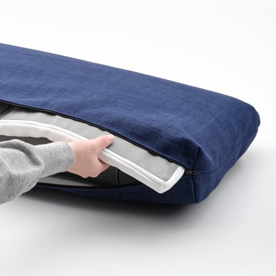 Person zipping open blue KLAGSHAMN back cushion, revealing inner mattress pad.
