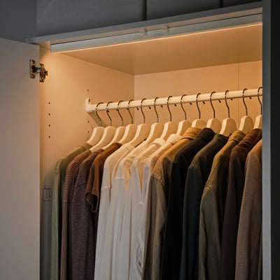 A closet with warm led lights illuminating clothes on hangers, activating automatically when the door opens.