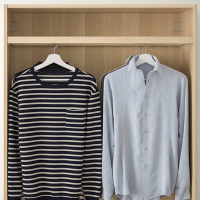 Wooden closet with two hanging shirts: one striped, one light blue. Shown with KOMPLEMENT rail.
