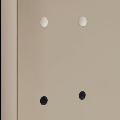 Four circular holes in a beige surface, two covered with white caps and two with black caps, showcasing furniture hole covers.