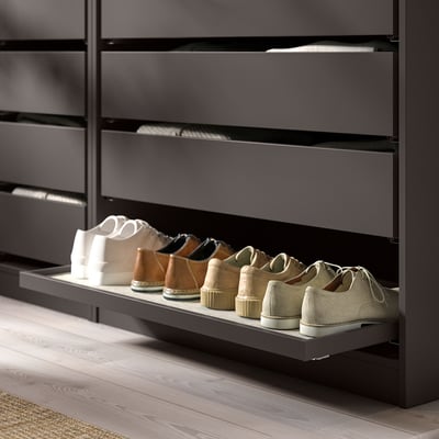 Modern dark gray shoe shelf unit, holding various shoes, in a closet.