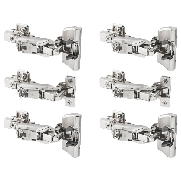 Six silver metallic hinges with intricate design for cabinet doors.