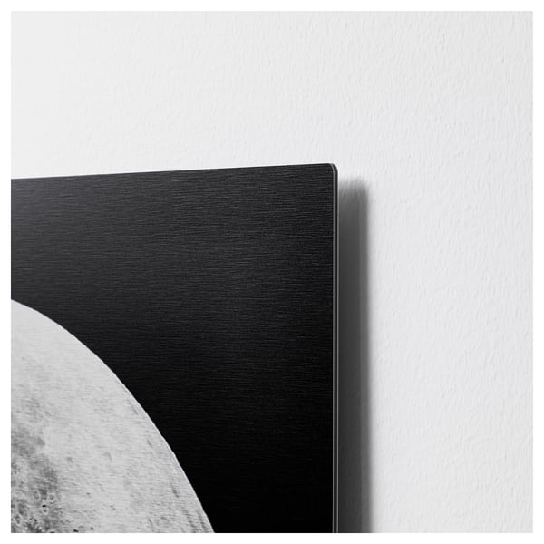 Black and white artwork on metallic surface, slightly raised edge, mounted on wall.