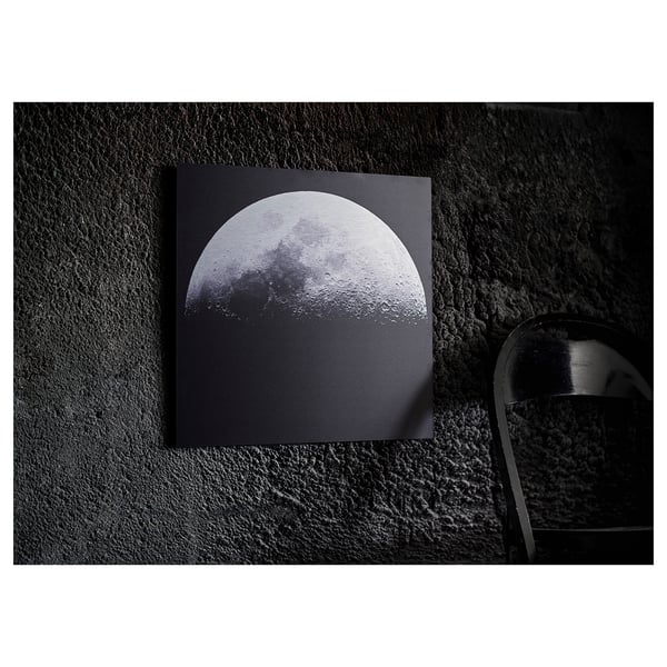 A KOPPARFALL black metal picture stand with a moon design, displaying a 3d-like effect against a dark wall.