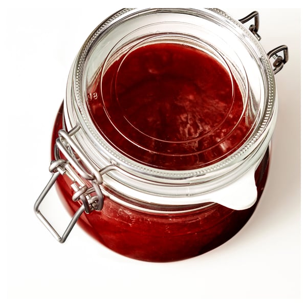 A glass jar with a metal clasp seal, containing red jam or preserve, used for food storage.