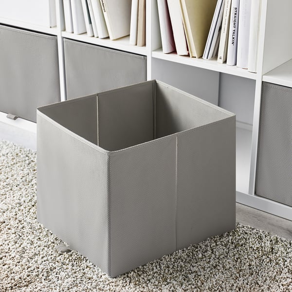 Empty gray folding storage box next to bookshelf on carpeted floor.