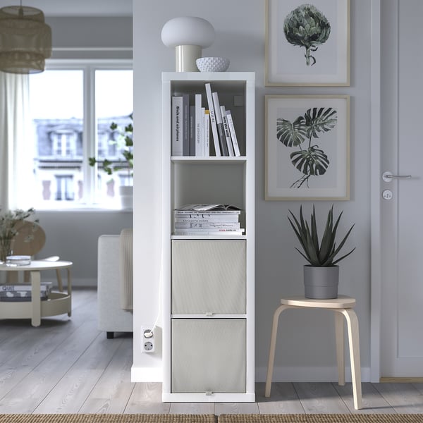 Stylish living room with white KOSINGEN storage box, gray plant, art prints, light wood stool.