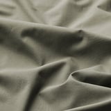 Close-up of soft, textured fabric in earthy green. Shows natural weave and gentle folds.