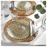Two woven placemats with glass plates, silverware, and glass cups in a rustic, natural design.
