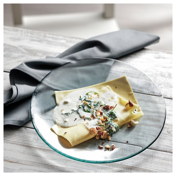 KRONKLEMATIS glass plate, green edge, round, holds folded food, sits on textured white tablecloth.