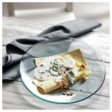 KRONKLEMATIS glass plate, green edge, round, holds folded food, sits on textured white tablecloth.