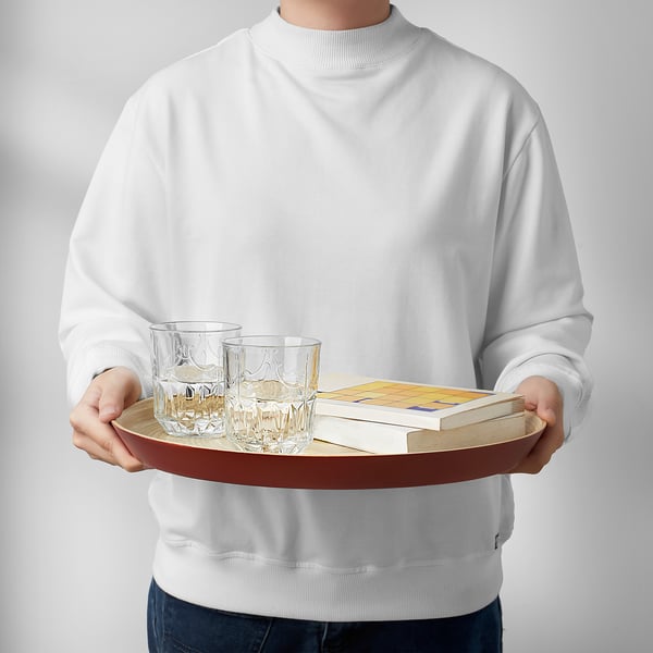 Person holding a bamboo serving tray with two glasses and books, perfect for serving or carrying items.