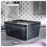 KUGGIS grey plastic box on a sink, rectangular shape, clear lid, holding a hair accessories.
