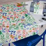 Colorful, patterned fabric displayed on a blue chair, ideal for sewing projects, with scissors, thread, and a sewing machine shown nearby.