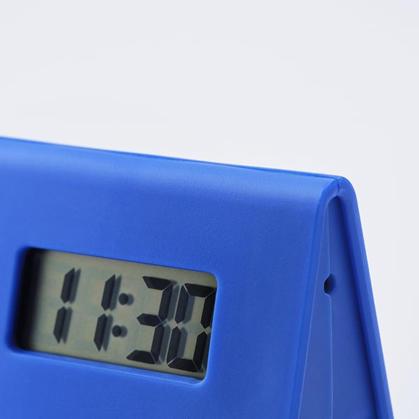 Small blue digital alarm clock, rounded edges, clear display showing time in dark room.