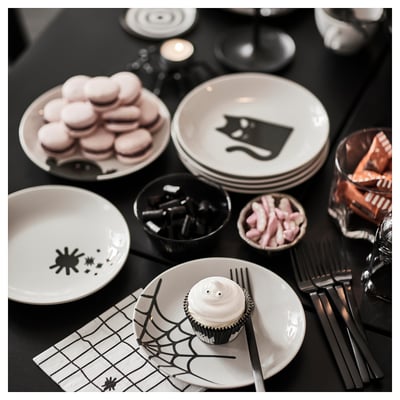 Four white KUSTFYR plates, each with black halloween-themed designs in different positions. Made of stoneware.