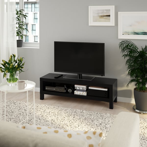 Modern LACK tv stand with flat screen, open storage, bed, coffee cup, plants, art prints, large window.