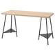 A LAGKAPTEN desk with a light wooden top and black metal legs, featuring a minimalist and modern design with triangular bases.