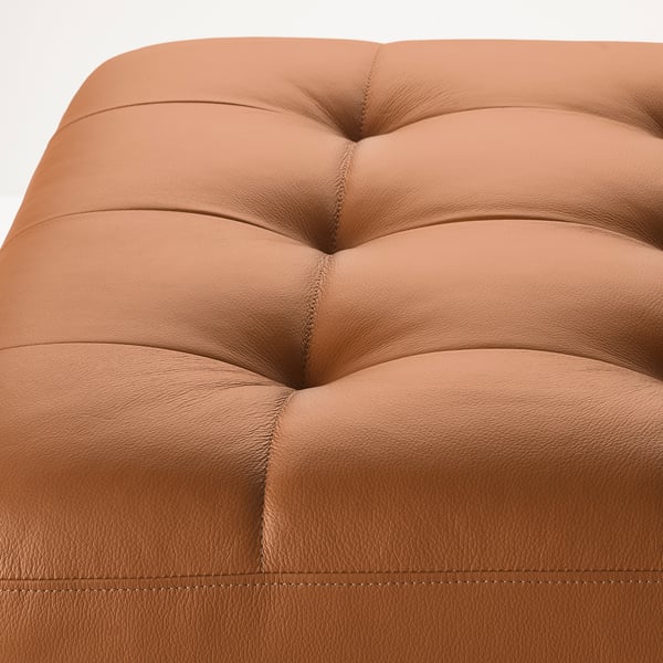 Close-up of a high-quality leather armchair with tufted back and seat, showcasing its luxurious texture and craftsmanship.